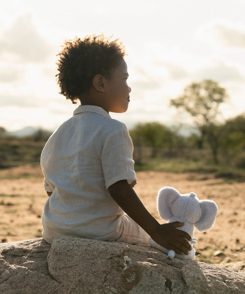 Enfant assis avec la peluche éléphant Safari Friends dans la nature