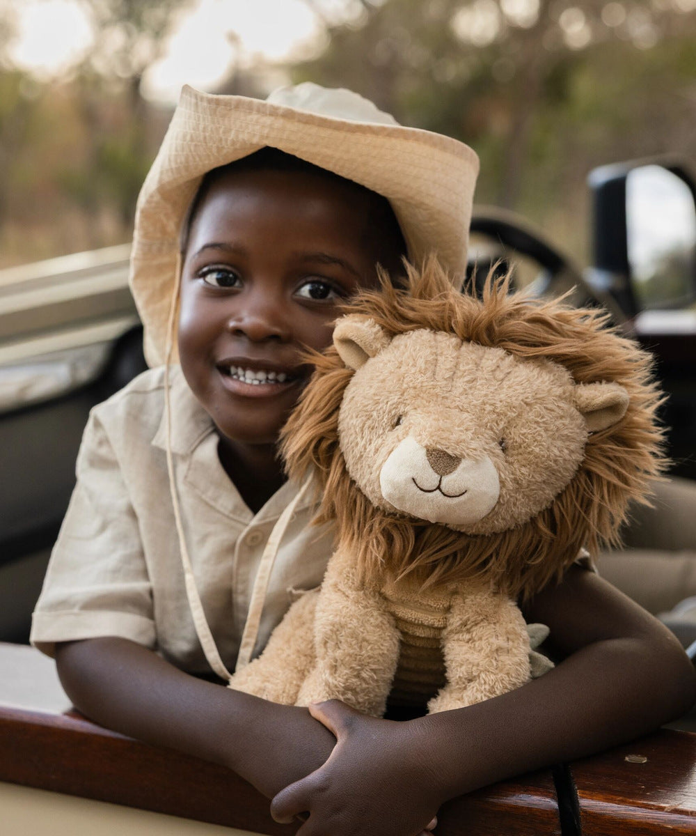 Enfant tenant la peluche lion Safari Friends contre lui