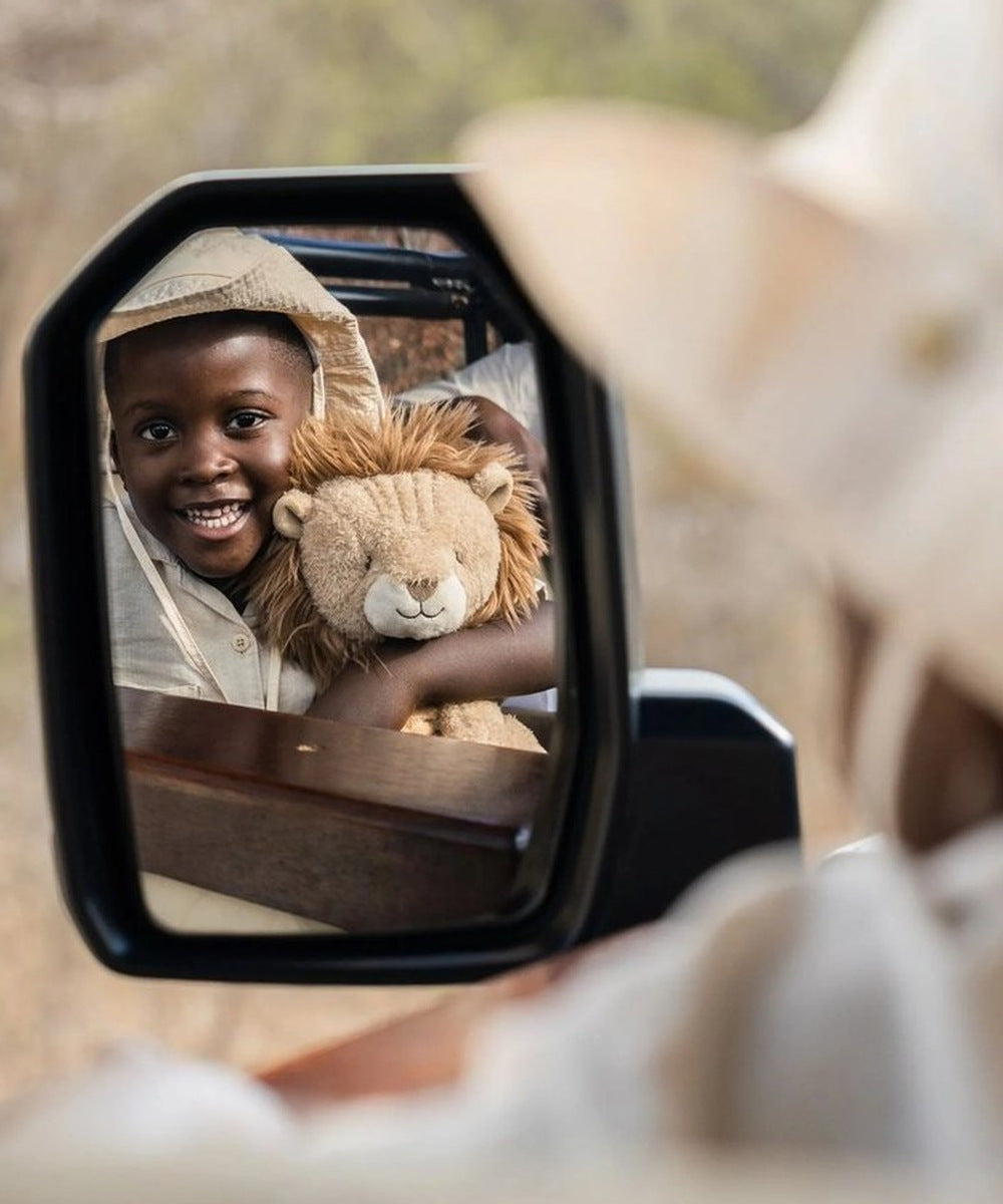 Enfant tenant la peluche lion Safari Friends, vue dans un rétroviseur