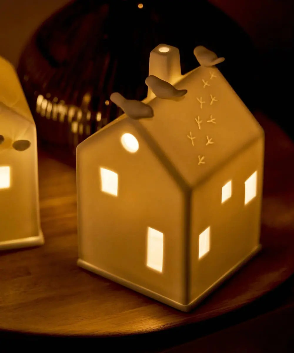Photophore maison en porcelaine blanche de la marque Räder avec petits oiseaux perchés sur le toit.
