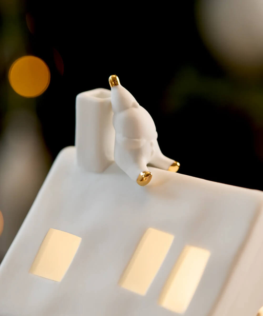 Gros plan du Père Noël en porcelaine aux détails dorés sur la cheminée de la maison Räder En attendant Rudolf