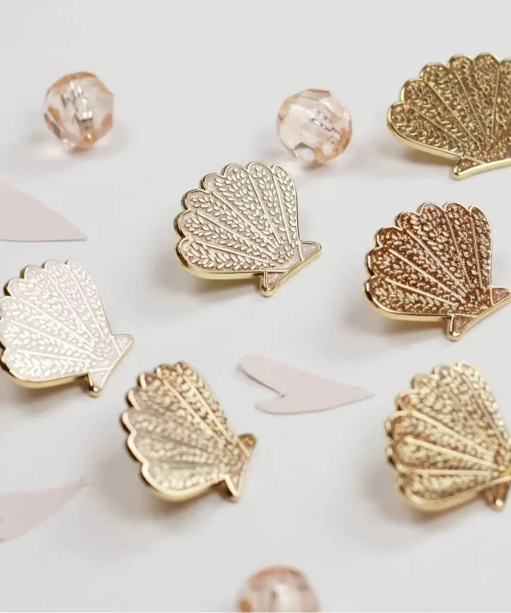 Pin’s Coquillage Doré Pailleté de My Lovely Thing posé sur une table