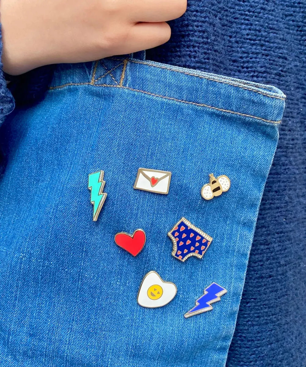 Pin's de la marque française Les Imprimeuses accrochés à un sac en jean