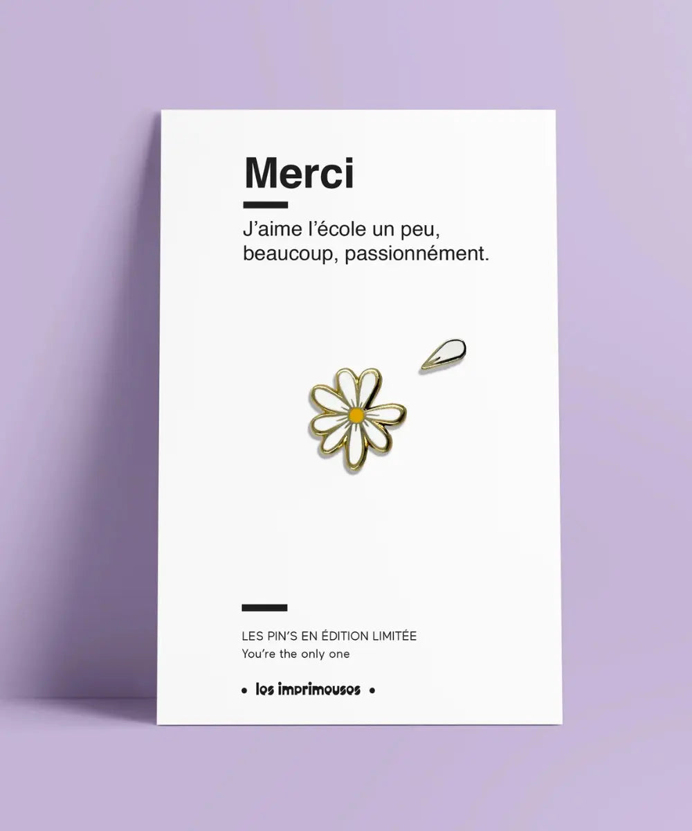 Petit pin's émaillé en forme de marguerite blanche aux contours dorés sur sa carte cadeau.