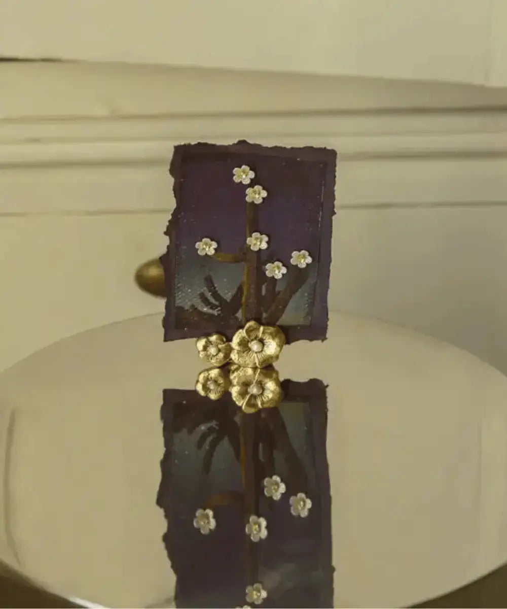 Porte carte en laiton Zoey fleurs de Doing Goods posé sur une table