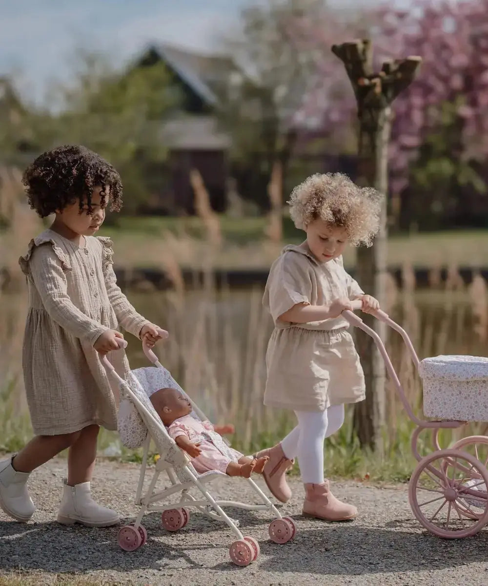 Enfants de 2 ans en train de jouer avec la poussette pour poupée de Little Dutch