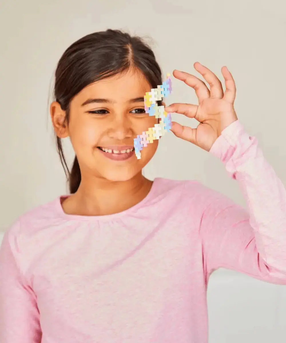 Enfant construisant une grande structure colorée avec les Plus-Plus Pastel.