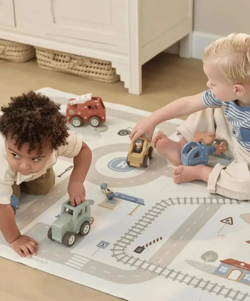 Enfants en train de jouer avec des voitures sur le tapis de jeu circuit de la marque Little Dutch