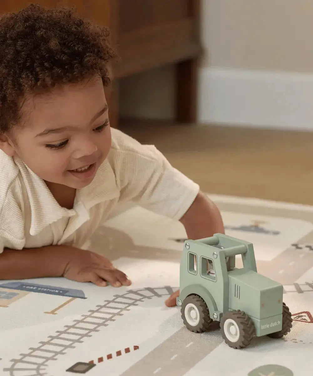 Enfant en train de jouer avec une voiture en bois sur le tapis de jeu Little Dutch