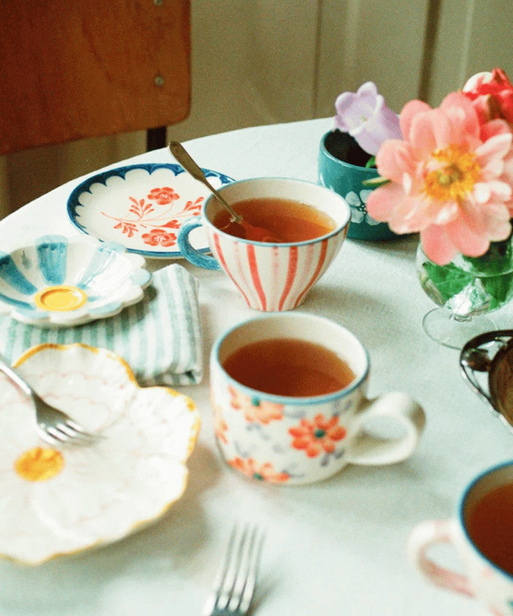 Tasse en céramique artisanale à rayures colorées peintes à la main marque Rice - posée sur une table à la décoration vintage