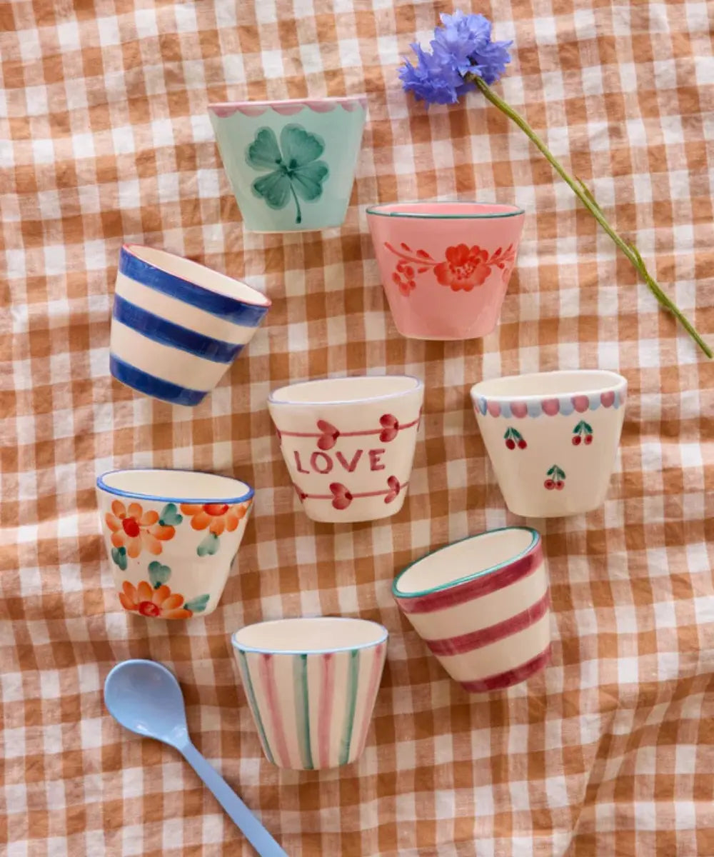 Tasse à expresso en céramique avec un trèfle peint à la main posé sur une table colorée
