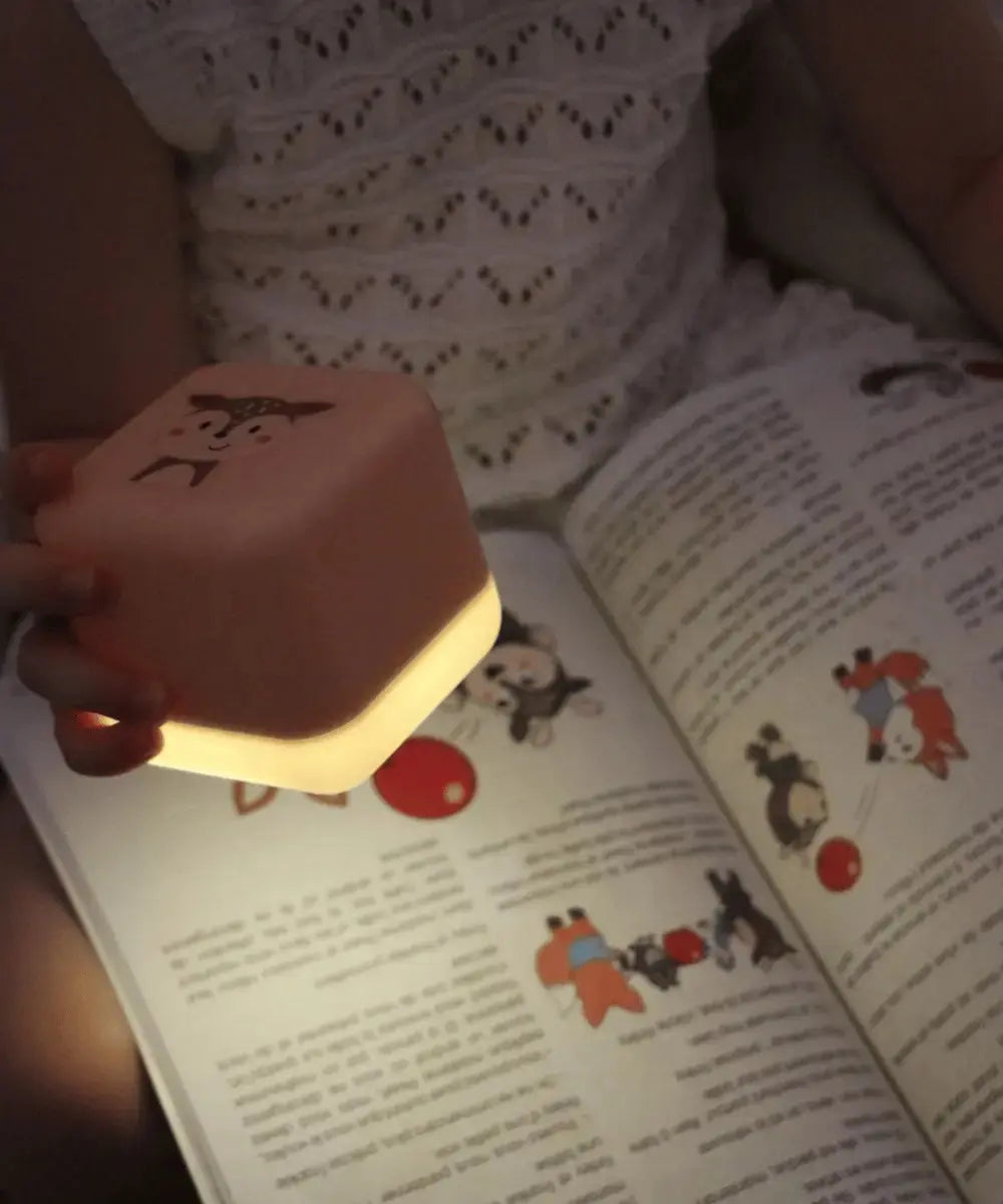 Vue de la veilleuse Cube B dans les mains d'un enfant en train de lire