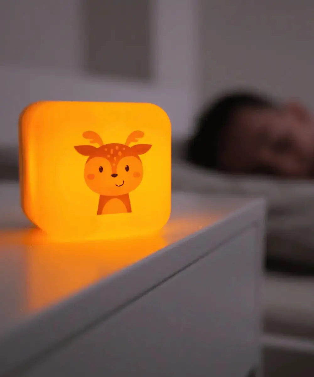 Vue de la veilleuse nomade Cube B posée sur la commode d'une chambre d'enfant : lumière chaude
